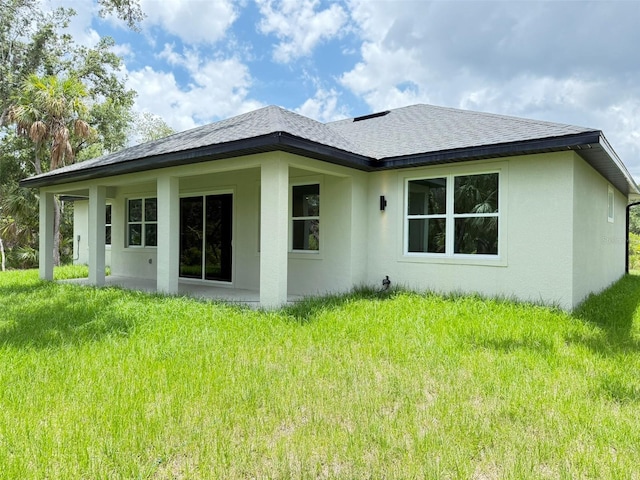 1074 Kacerik St, North Port, FL 34288 - rear view of house featuring stucco siding, a shingled roof, and a lawn