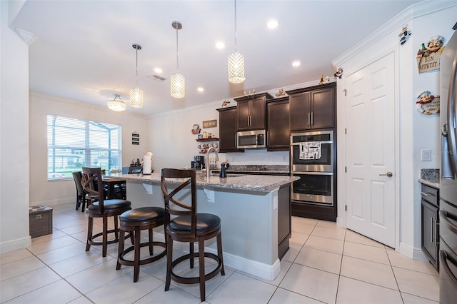 kitchen featuring stainless steel appliances, a center island with sink, and pendant lighting