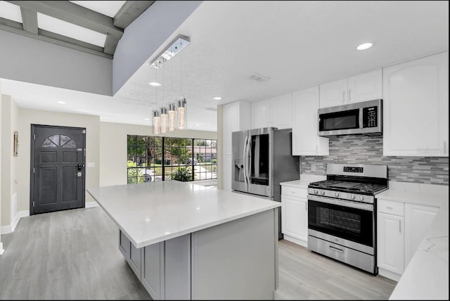 kitchen featuring decorative light fixtures, a center island, stainless steel appliances, and white cabinetry