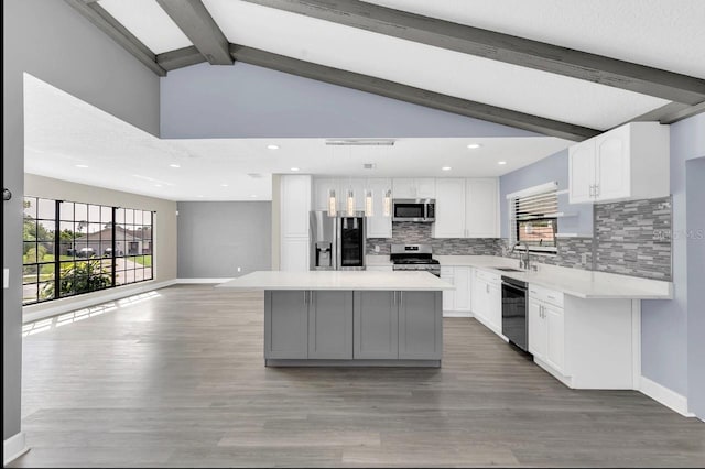 kitchen with a center island, beamed ceiling, white cabinets, and stainless steel appliances