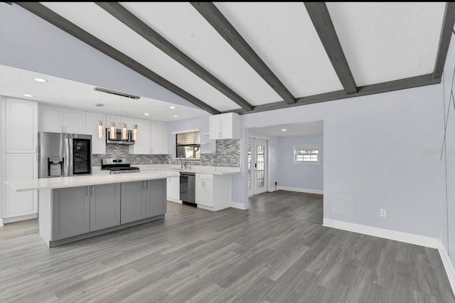 kitchen featuring lofted ceiling with beams, hanging light fixtures, a kitchen island, white cabinetry, and stainless steel appliances