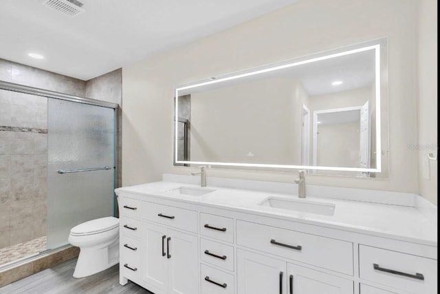 bathroom with hardwood / wood-style floors, vanity, toilet, and a shower with door