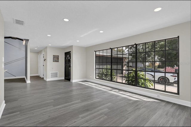 unfurnished living room featuring hardwood / wood-style flooring and a textured ceiling