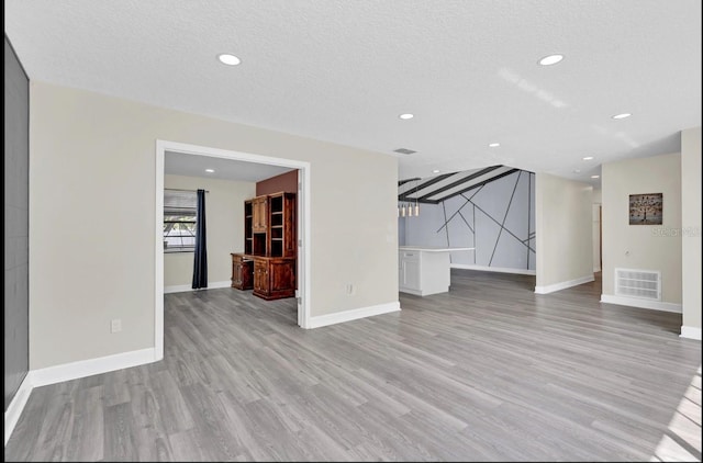 unfurnished living room with a textured ceiling and light wood-type flooring