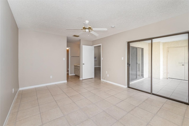 unfurnished bedroom featuring a textured ceiling, connected bathroom, ceiling fan, and light tile patterned floors