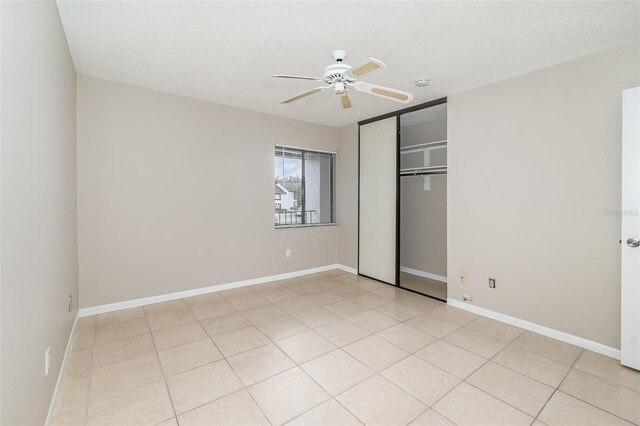 unfurnished bedroom with a textured ceiling, ceiling fan, and a closet