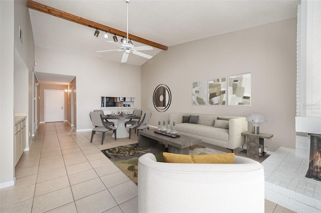 living room featuring vaulted ceiling with beams, a textured ceiling, ceiling fan, and light tile patterned flooring