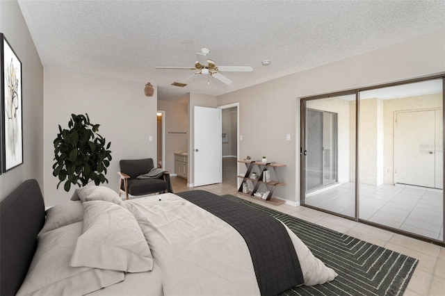 tiled bedroom featuring connected bathroom, ceiling fan, and a textured ceiling