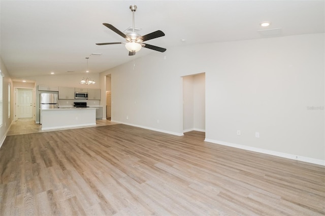 unfurnished living room featuring light wood-type flooring, vaulted ceiling, and ceiling fan with notable chandelier