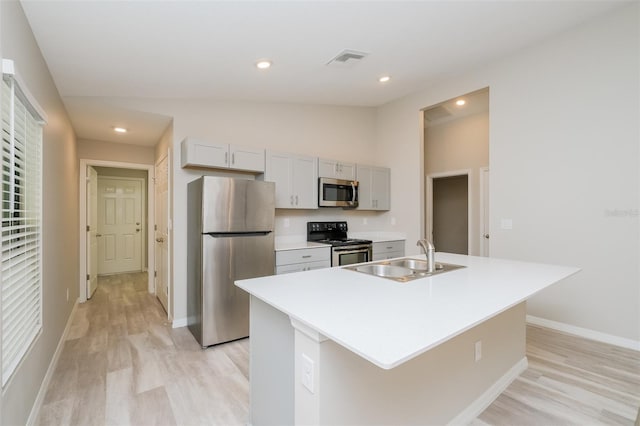 kitchen featuring light hardwood / wood-style floors, sink, appliances with stainless steel finishes, an island with sink, and lofted ceiling