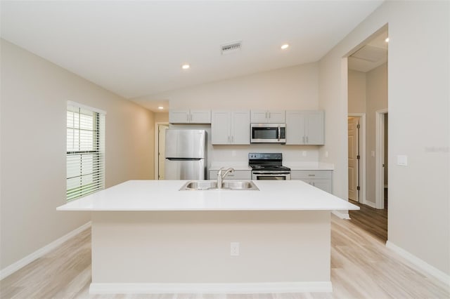 kitchen with stainless steel appliances, light hardwood / wood-style floors, sink, an island with sink, and lofted ceiling