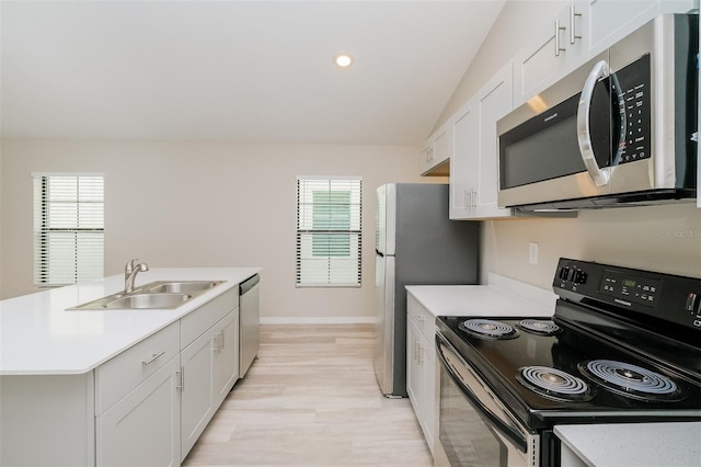 kitchen featuring light wood-type flooring, appliances with stainless steel finishes, sink, white cabinets, and a kitchen island with sink