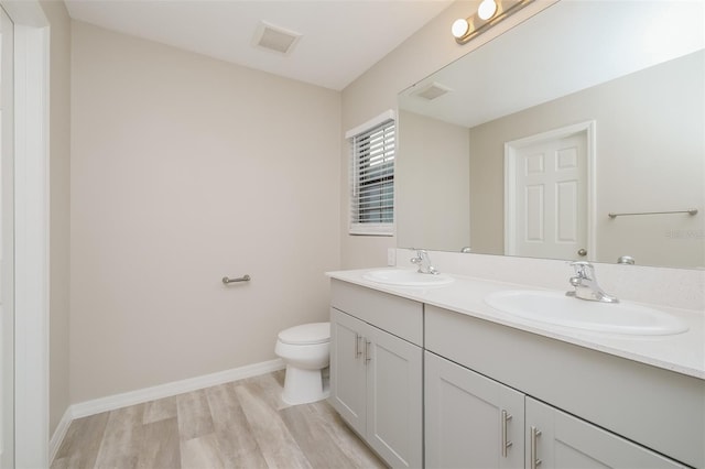 bathroom with toilet, vanity, and hardwood / wood-style floors