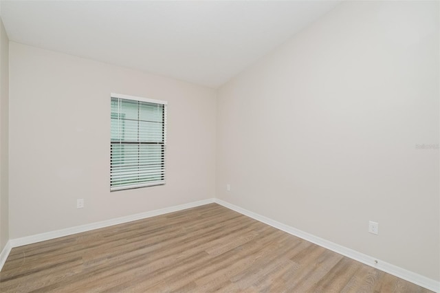 spare room with light hardwood / wood-style floors and lofted ceiling