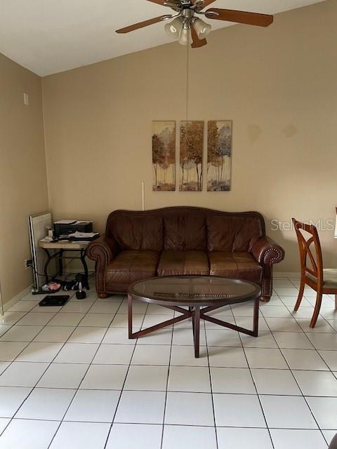 living room featuring lofted ceiling, light tile patterned floors, and a ceiling fan