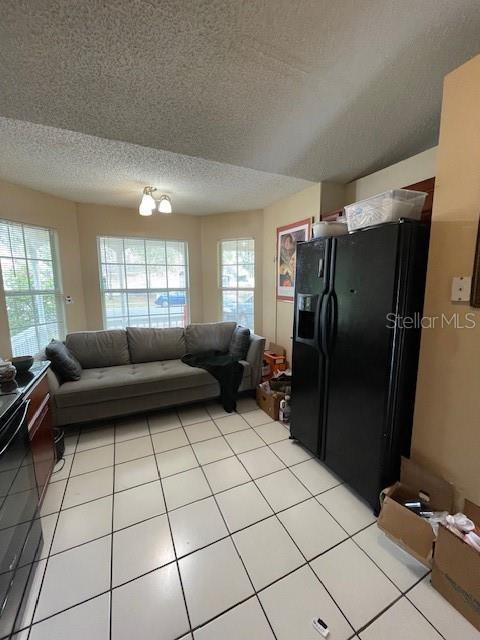 living room featuring light tile patterned floors, a textured ceiling, and a healthy amount of sunlight