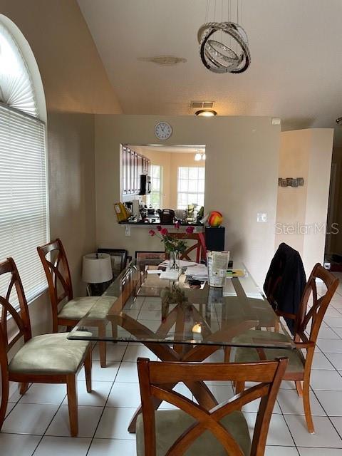 dining space featuring lofted ceiling, light tile patterned floors, and visible vents