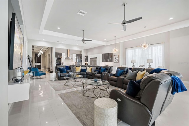 living room featuring ceiling fan with notable chandelier and a raised ceiling