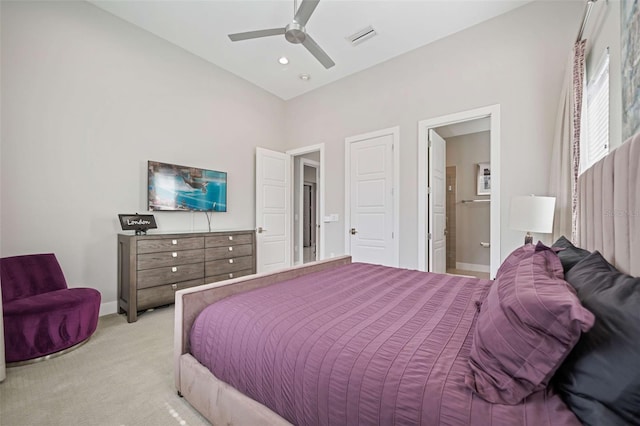 bedroom with ensuite bathroom, light carpet, and ceiling fan