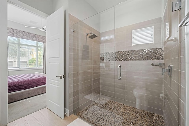 bathroom with ceiling fan, a shower with door, and tile patterned flooring