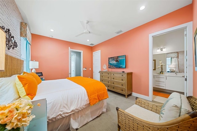 carpeted bedroom with ensuite bathroom and ceiling fan