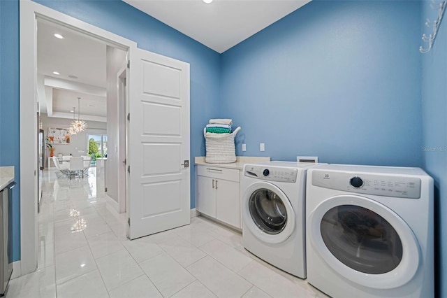 laundry area featuring light tile patterned flooring, cabinets, a chandelier, and washer and dryer