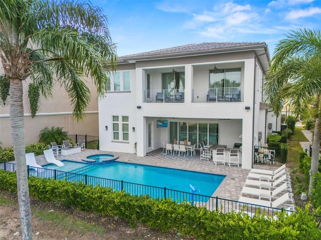 back of property with a bar, a balcony, a swimming pool with hot tub, and a patio