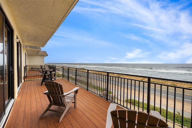 wooden terrace featuring a water view and a beach view