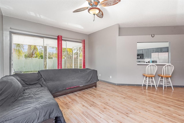 bedroom featuring hardwood / wood-style flooring, a textured ceiling, ceiling fan, and stainless steel fridge