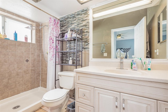 bathroom featuring curtained shower, vanity, ceiling fan, and toilet