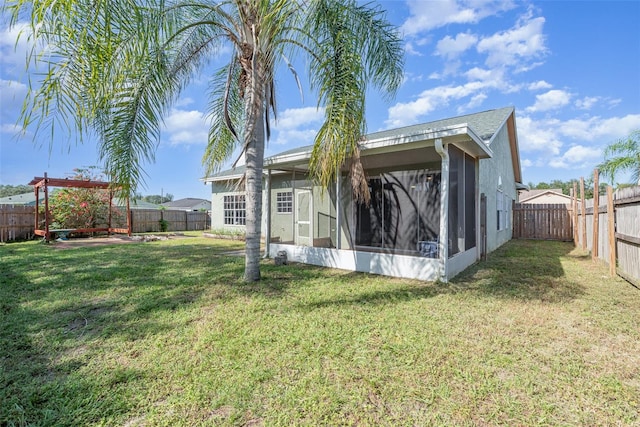 rear view of house featuring a sunroom and a lawn