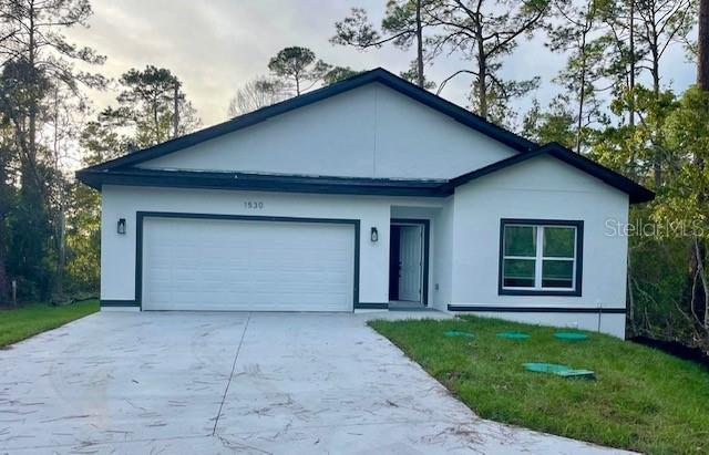 single story home with a garage and a front lawn