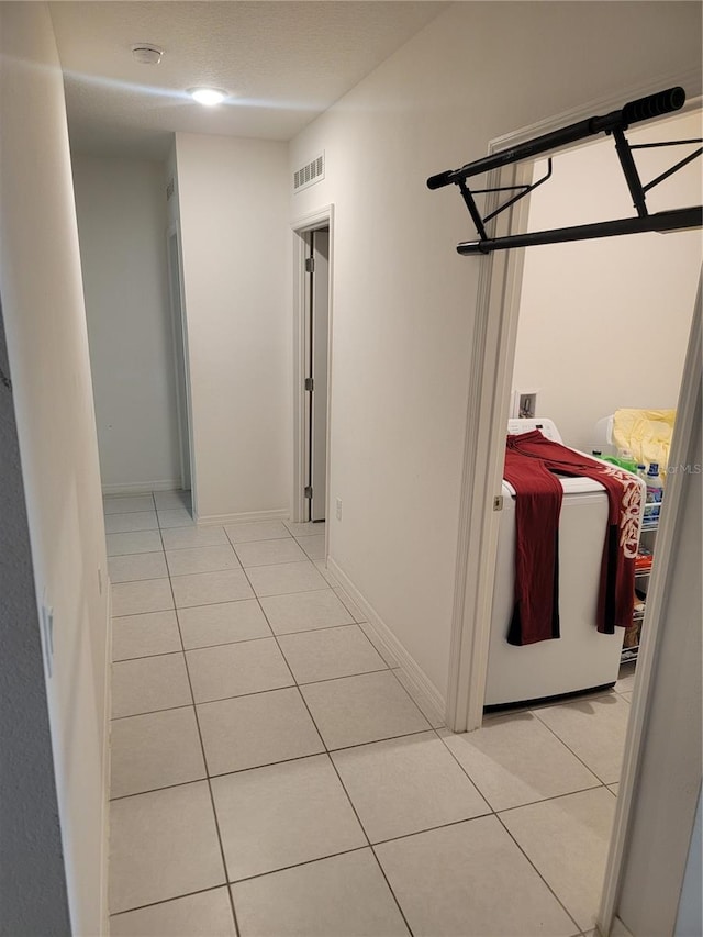 hallway featuring light tile patterned floors and washer / dryer