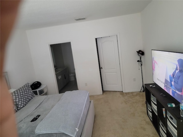 bedroom with ensuite bath and light carpet