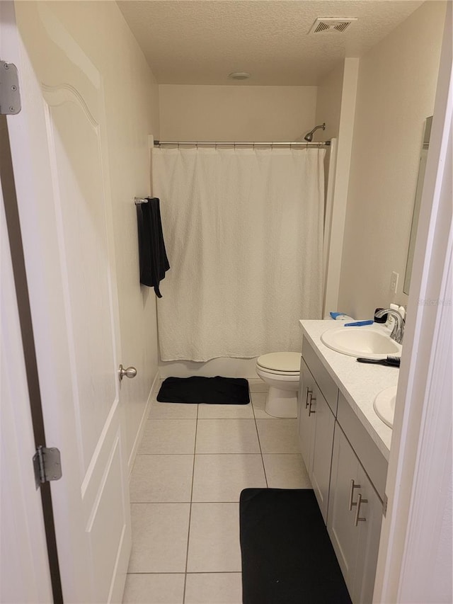 bathroom with toilet, vanity, a textured ceiling, and tile patterned floors