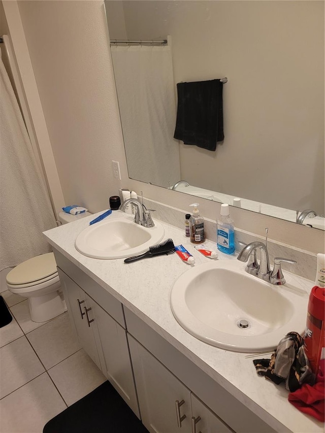 bathroom with toilet, vanity, and tile patterned floors