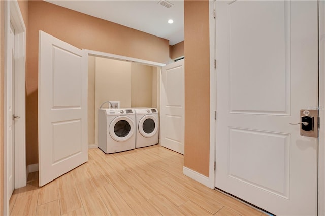 laundry room featuring separate washer and dryer and light hardwood / wood-style flooring