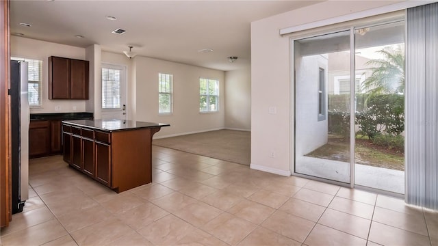 kitchen with stainless steel refrigerator, light tile patterned flooring, and a kitchen island