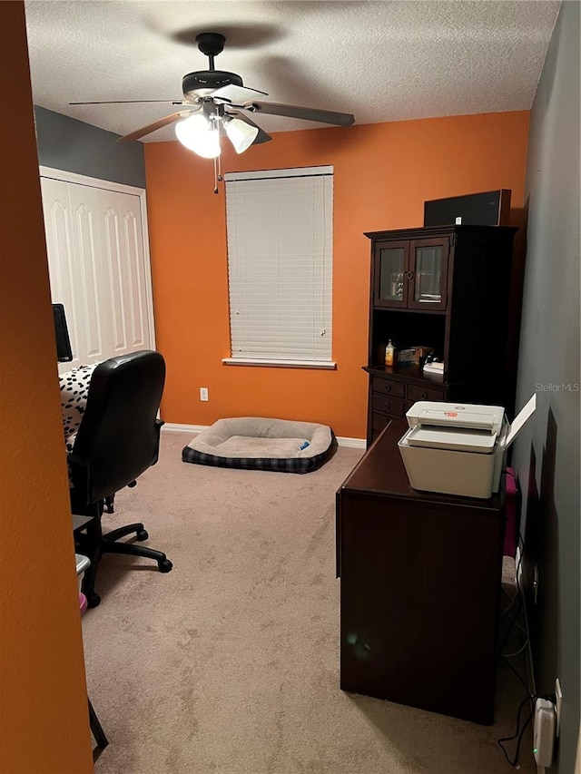 carpeted office featuring a textured ceiling and ceiling fan