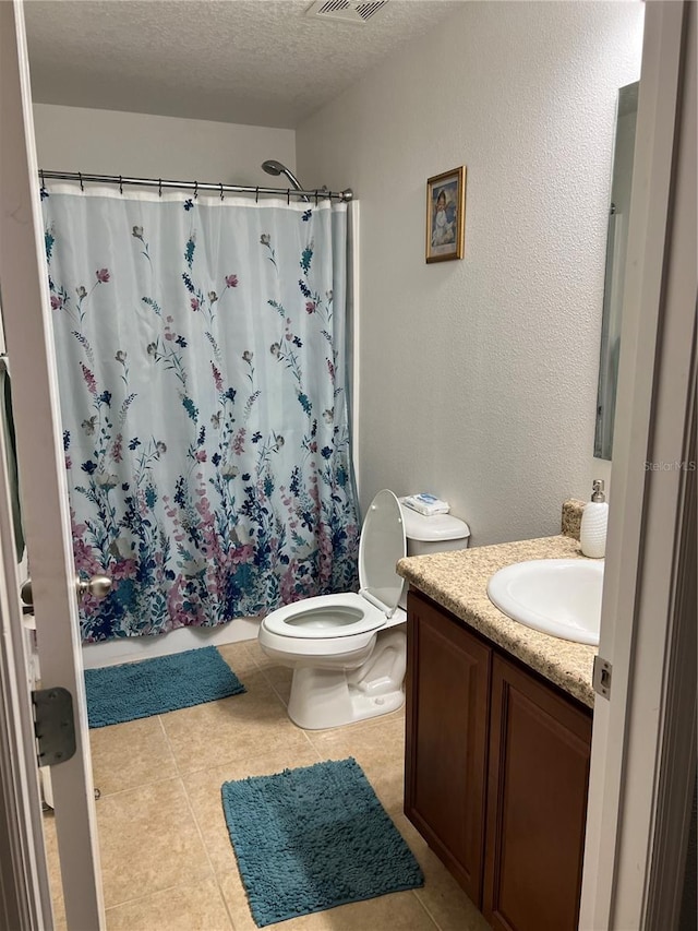 bathroom with tile patterned flooring, vanity, toilet, and a textured ceiling