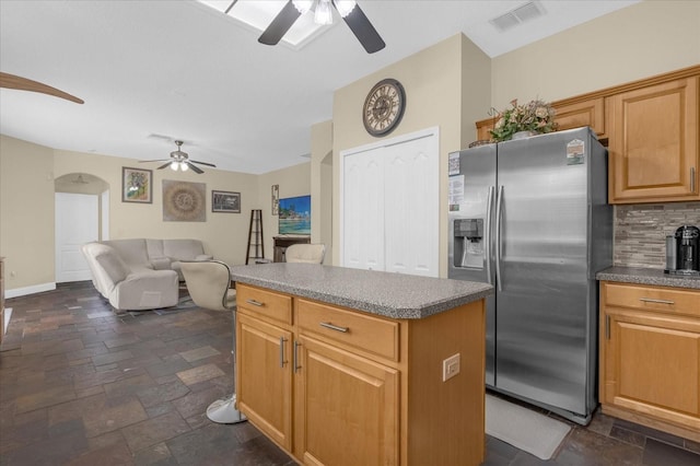 kitchen featuring stainless steel refrigerator with ice dispenser, a center island, and tasteful backsplash