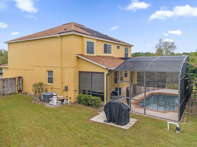 back of house featuring central AC, glass enclosure, a patio area, a yard, and a fenced in pool