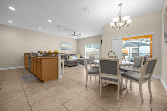 dining area featuring sink, light tile patterned floors, and ceiling fan with notable chandelier