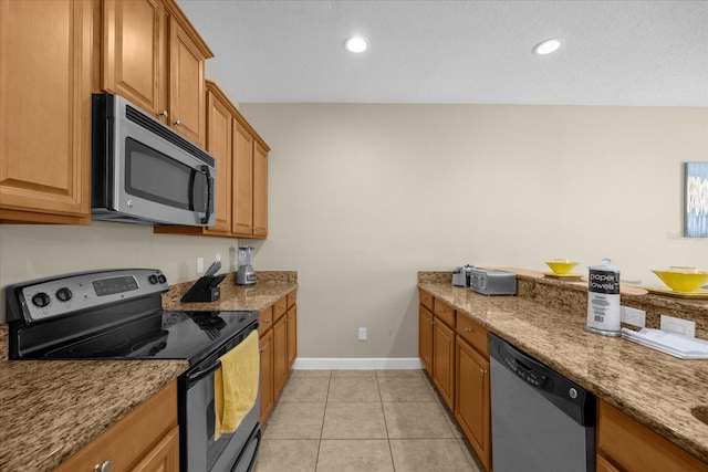 kitchen featuring light stone counters, light tile patterned flooring, a textured ceiling, and appliances with stainless steel finishes