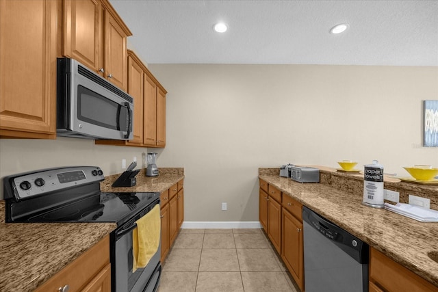 8962 Cuban Palm Rd, Kissimmee, FL 34747 - kitchen with stainless steel appliances, brown cabinets, baseboards, light tile patterned floors, and light stone countertops
