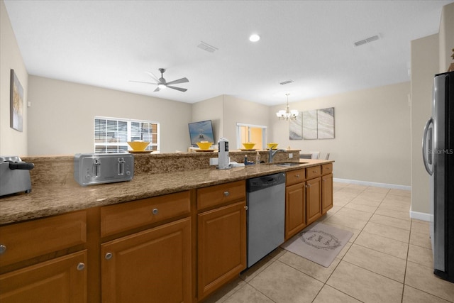 kitchen with light stone countertops, ceiling fan with notable chandelier, stainless steel appliances, sink, and decorative light fixtures