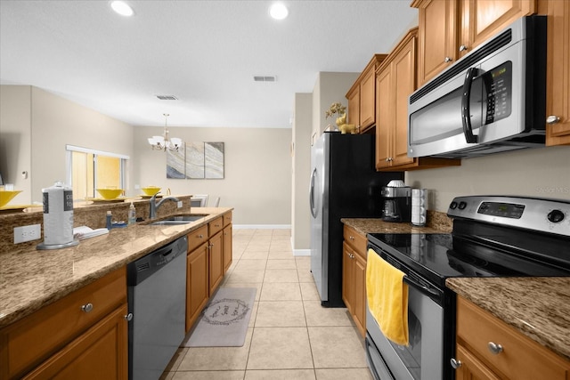 kitchen with an inviting chandelier, sink, light tile patterned floors, light stone countertops, and appliances with stainless steel finishes