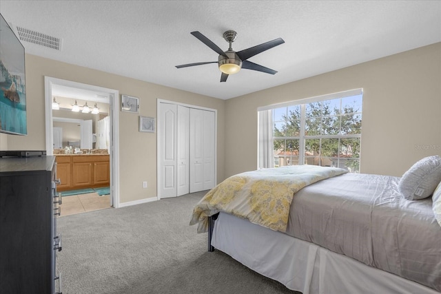 bedroom featuring connected bathroom, ceiling fan, light colored carpet, a textured ceiling, and a closet