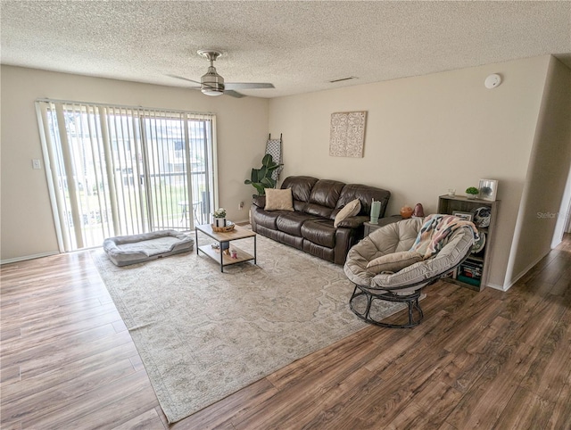 living room featuring ceiling fan, dark wood-type flooring, and a textured ceiling