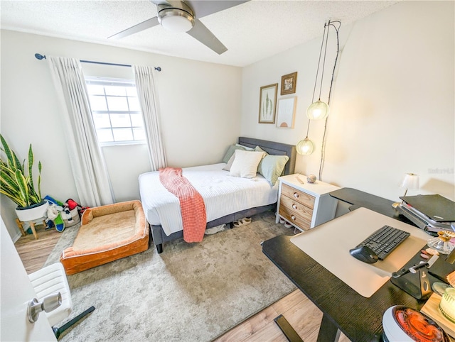 bedroom with a textured ceiling, hardwood / wood-style flooring, and ceiling fan